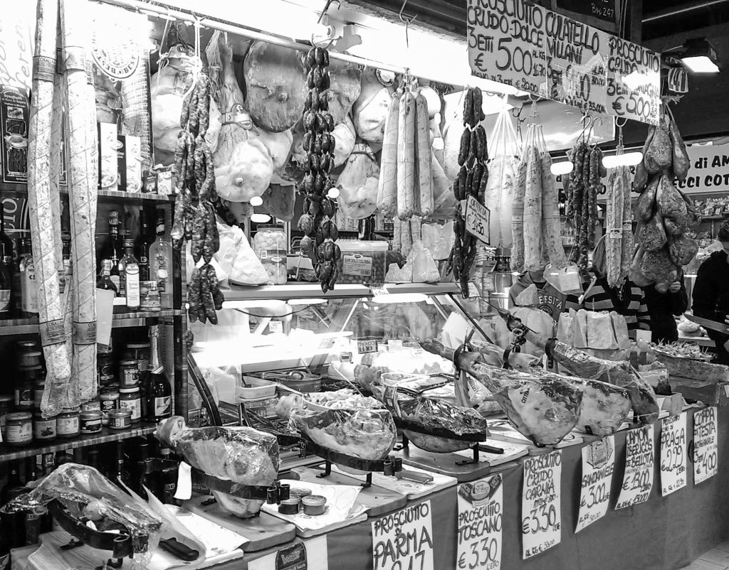 Zavesené šunky a salámy v stánku na trhu Trionfale, čierno-biela fotografia