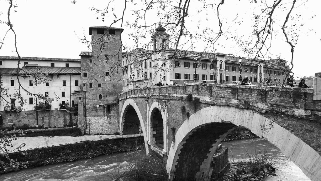 Čierno biela foto mosta, za ním budova, niekde v Ríme
