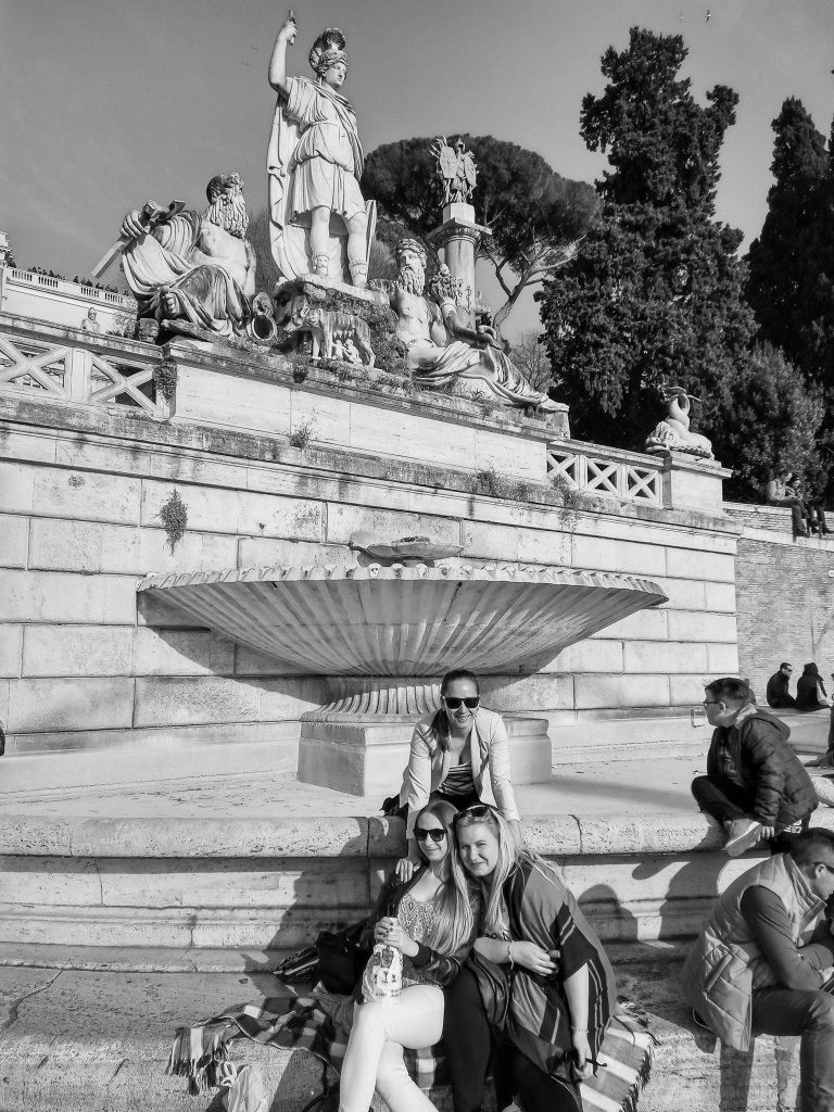 čierno biela foto nás troch žien ako sedíme na piazza di popolo pod sochou