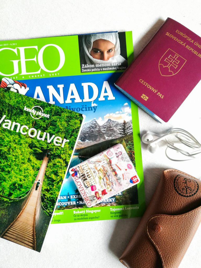 Na bielom podklade bedeker Lonely Planet Vancouver, za ním časopis Geo o Kanade, pas, okuliare, slúchadlá a zrkadlo so slovenským motívom.