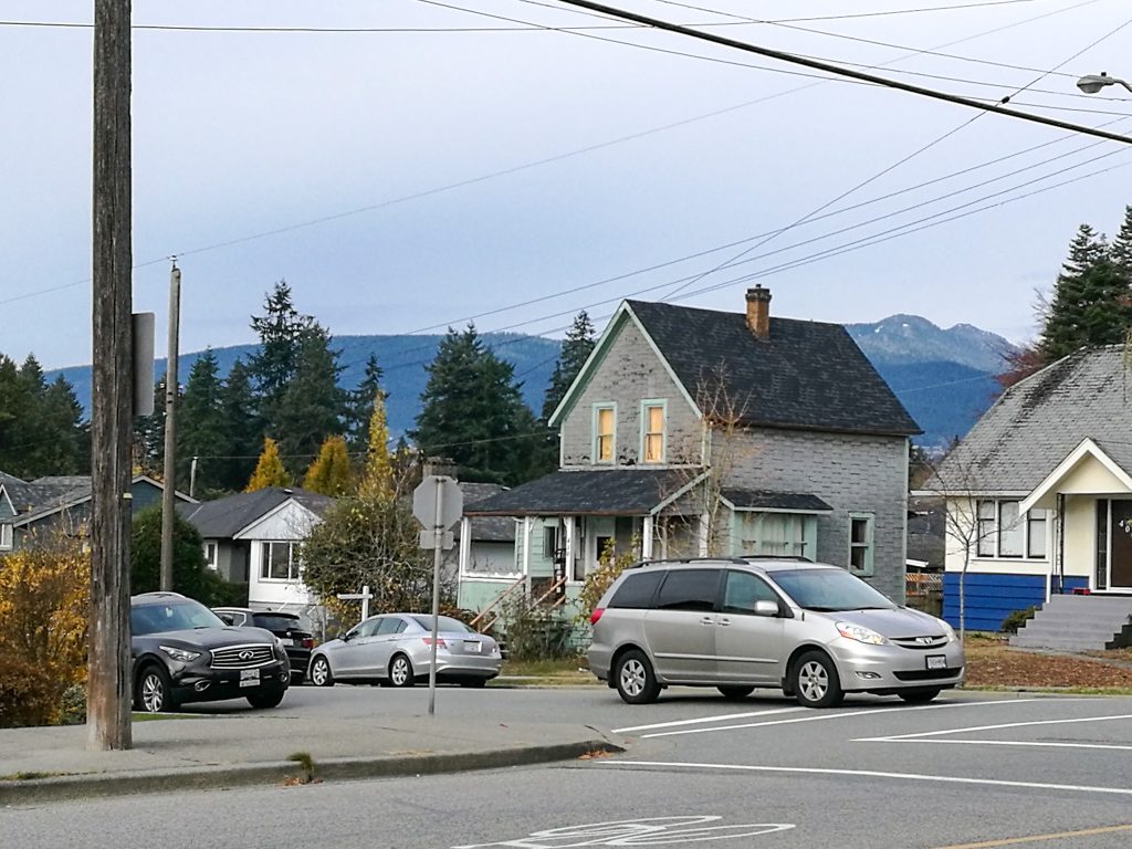 Fotografia ulice, kde je vidieť typické americké domy s ich terasami, plus auto na križovatke