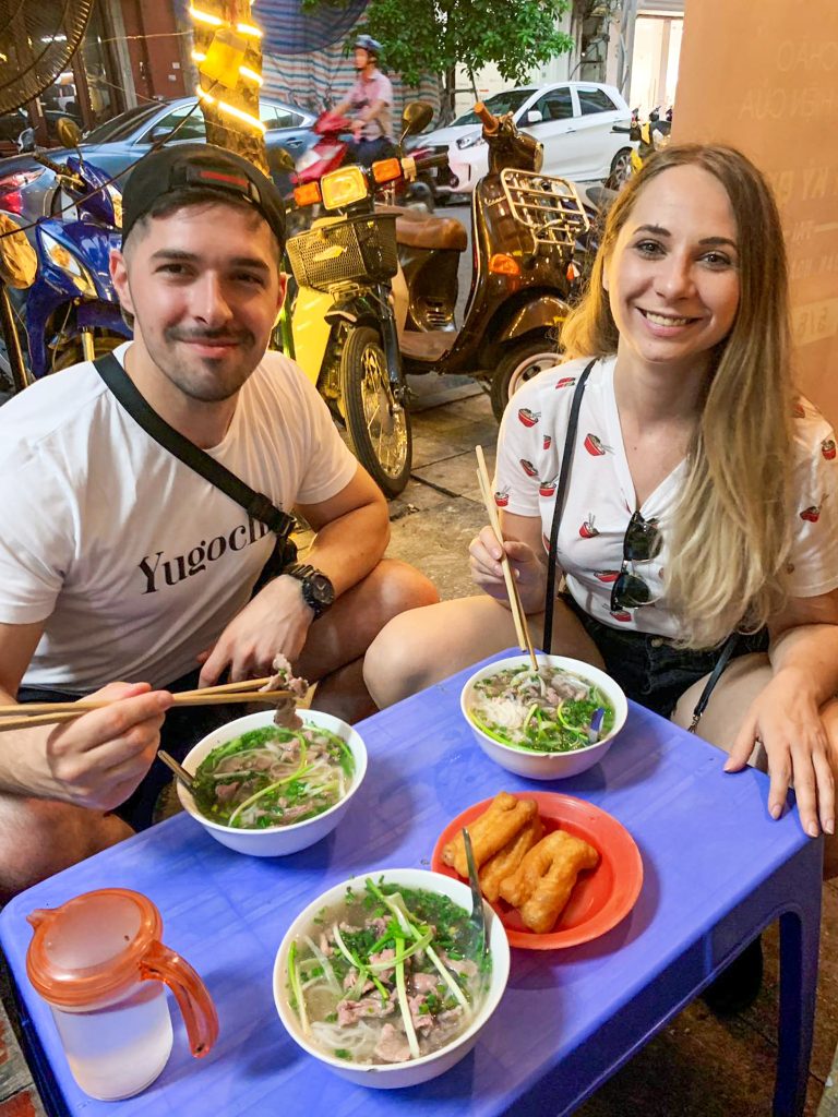Ja a Igor pri malom plastovom stole pózujeme pri jedení vietnamskej polievky