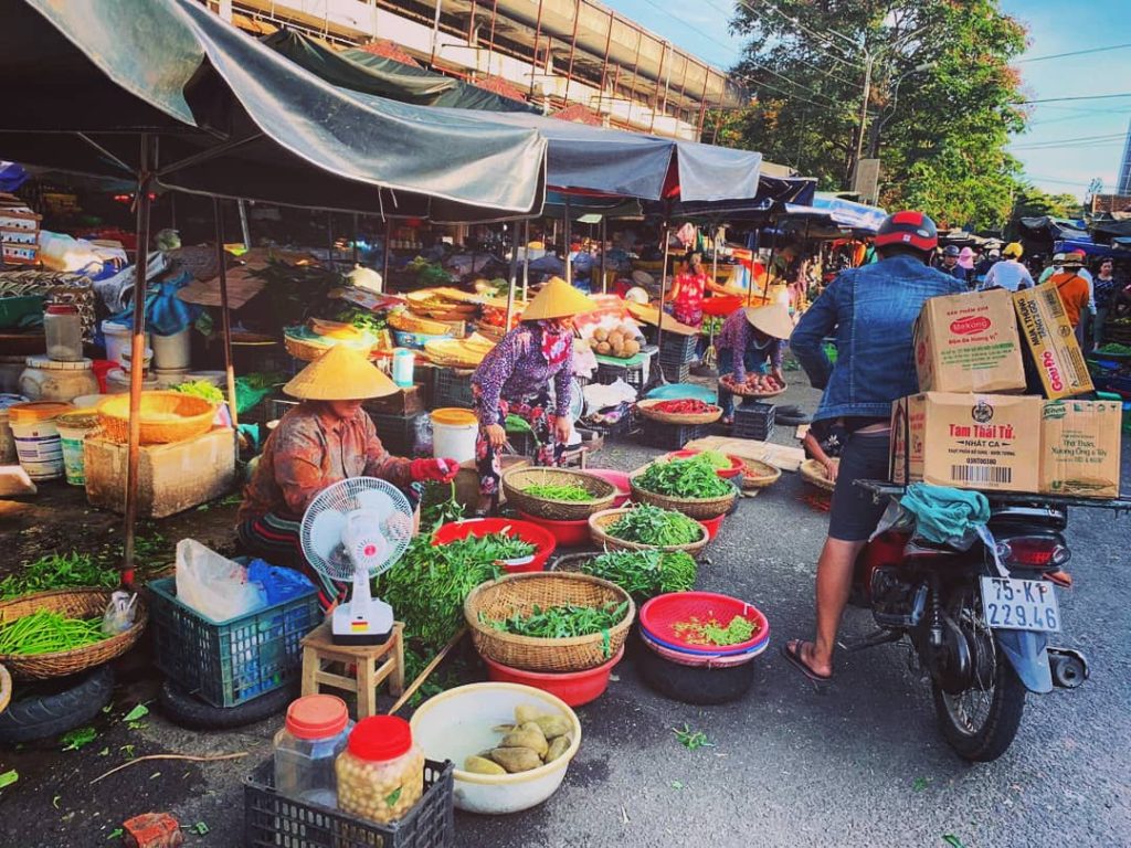 Vietnamky na miestnom trhu predávajú ovocie v obrovských misách ležiacich na zemi
