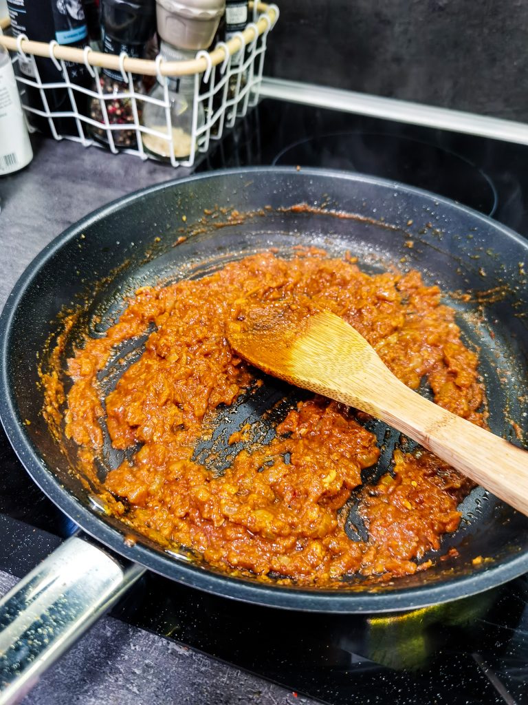 Hustá pasta zmiešaná z rajčinového pretlaku, korenia a cibule sa pečie na panvici