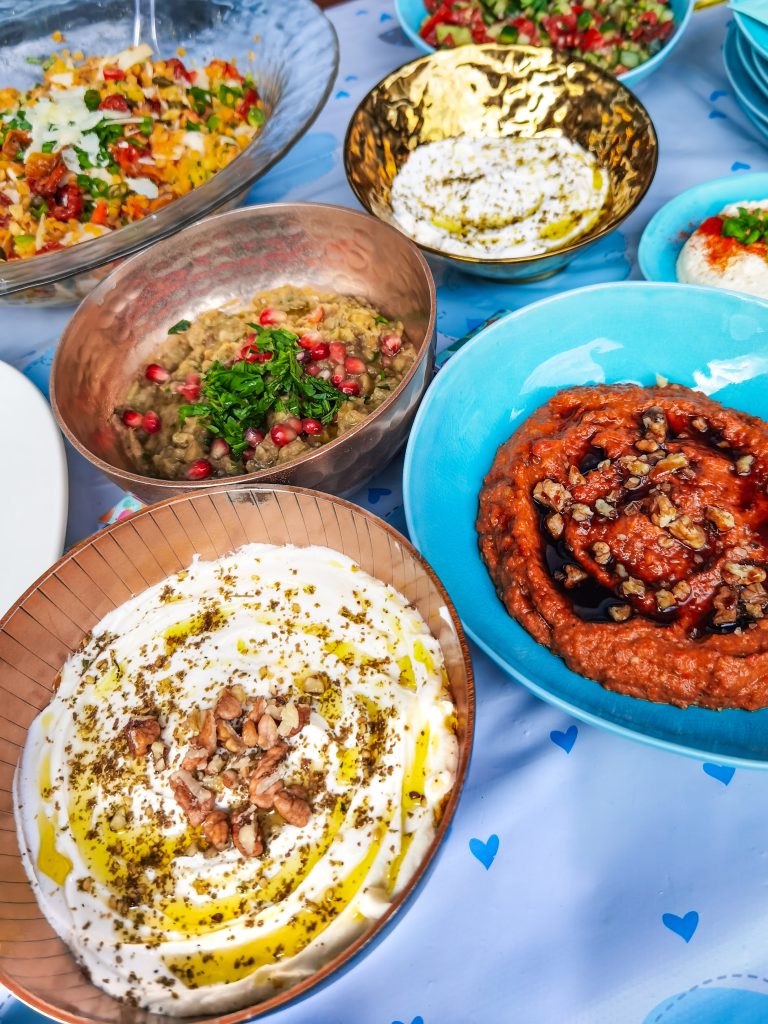 Misky s rôznymi predjedlami na stole - muhammara, labneh, baba ganoush, izraelský šalát a šošovicový šalát
