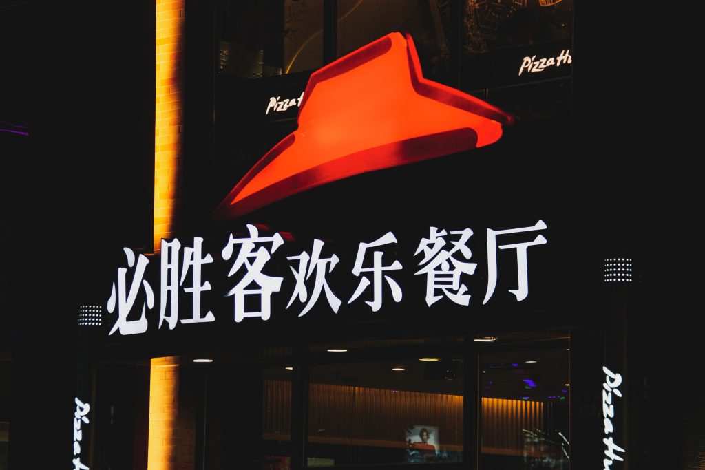 Logo Pizza Hut (červený klobúk) s čínskym nápisom pod tým