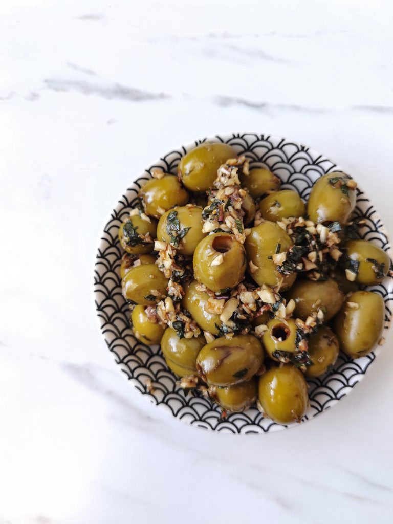 Zelené olivy v miske nakladané v melase, cesnaku, orechoch a mäte