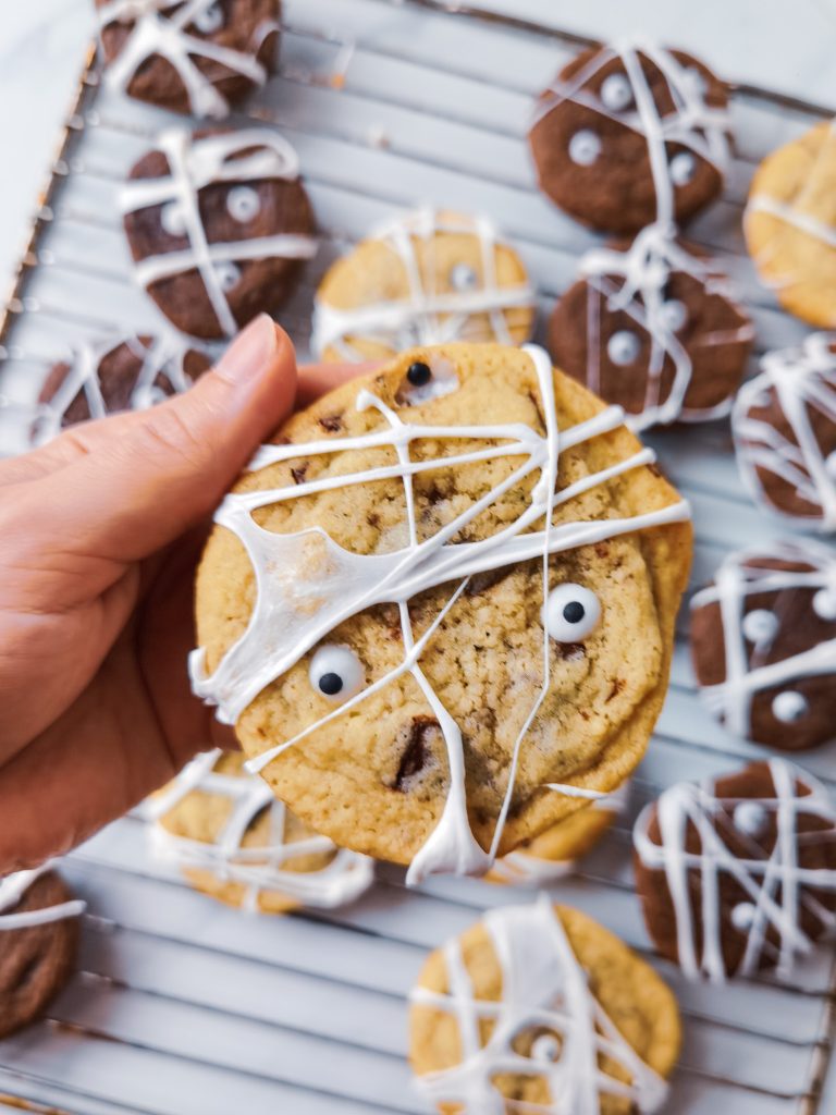 Jeden strašidelný cookie v popredí béžovej farby s dvoma očami a popretkávaný "pavučinou"