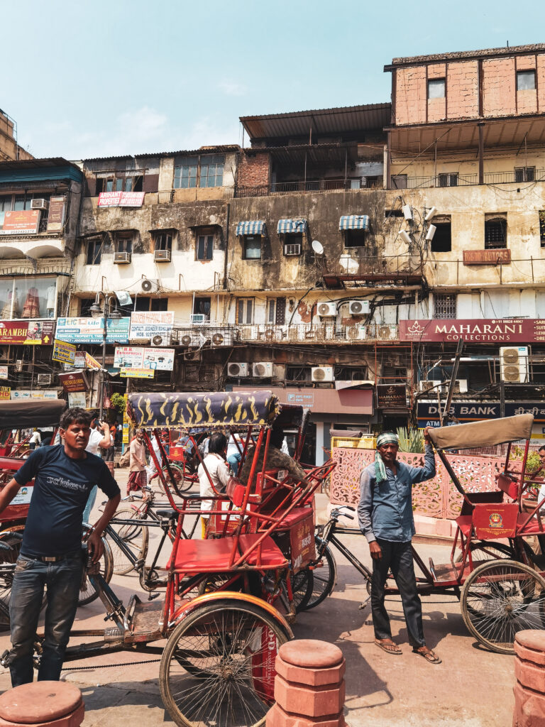 Ošarpané budovy starého mesta a pred ním čakajúci vodiči červených ríkš